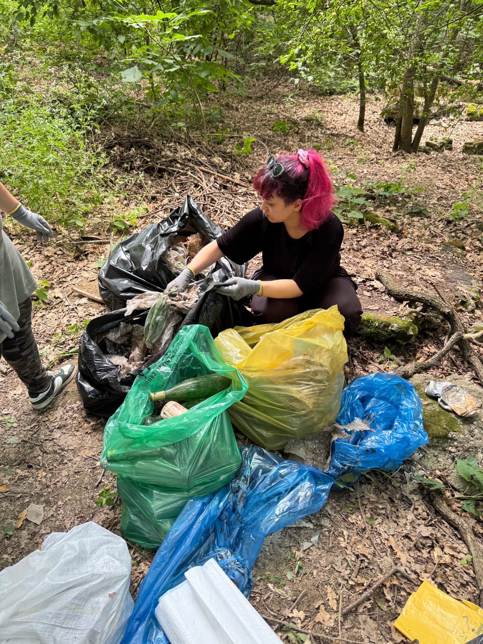 Voluntară separând deșeurile în saci colorați